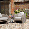 image of single seat rattan garden armchair on gravel back garden, next to small stone side table with matching 2 seat sofa on the other side