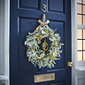 eucalyptus and lamb's ear wreath lit by warm white LEDs hanging on a navy blue front door