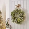 LED eucalyptus and lamb's ear wreath, displayed on the back of a white living room door with a christmas tree blurred in the background to the left