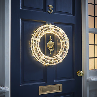acrylic warm white light-up wreath on the outside of a navy blue front door