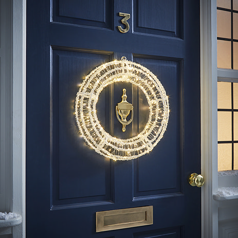 acrylic warm white light-up wreath on the outside of a navy blue front door