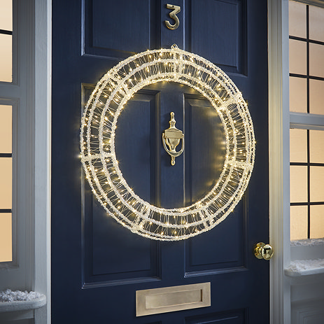 acrylic LED wreath hung on the front of a navy blue door