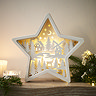 white wooden star with carved intricate scene lit up by LEDs in its middle, placed on a mantlepiece.