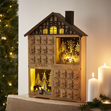 close up on drawers of wooden advent calendar, filled with mini chocolate coins and toffees placed on the mantlepiece.