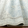 image of vintage patterned blue and white rug ruched up slightly to show its thinness