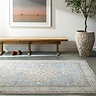 image of blue vintage patterned rug on grey floor in front of oak bench and potted plant
