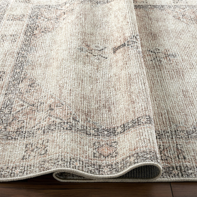 close up image of light brown rug slightly ruched to show its thinness