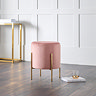 image of pink velvet pouffe with gold accent legs, stood on warm wooden flooring with gold console table in the background