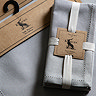 image of dove grey pack of 4 linen style napkins wrapped with cream ribbon and brown cardboard brand label