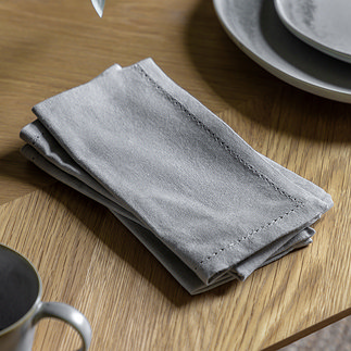 image of plain dove grey linen style napkin folded on wooden table next to ceramic plates