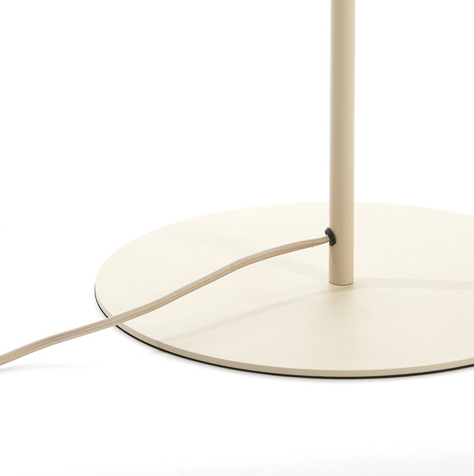 image cut out on white background of lamp's cream circular base with cream cable extending from the slim body