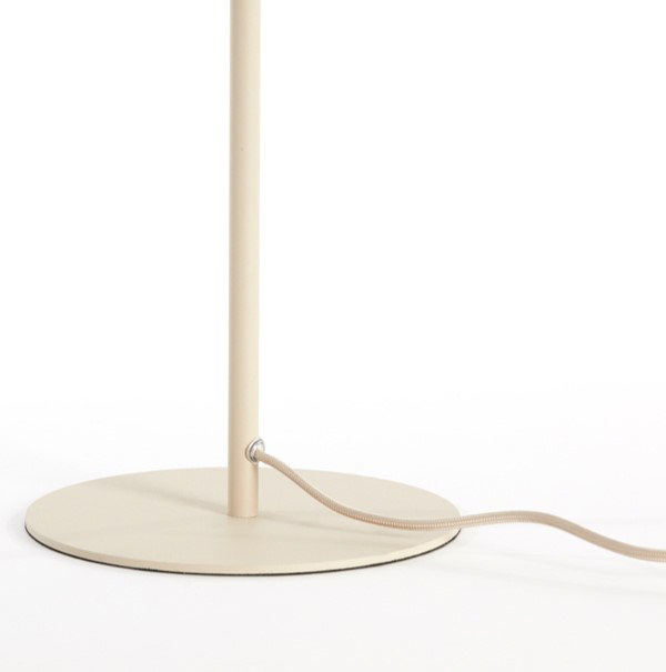 close up on bottom half of thin cream coloured lamp shade with circular base and cream wire leading out