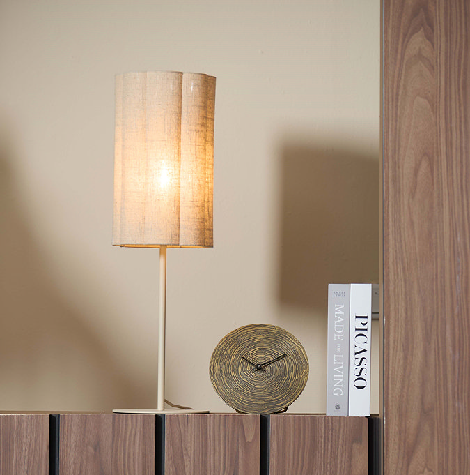 image of linen cylindrical table lamp on a wooden sideboard next to stacked coffee table books