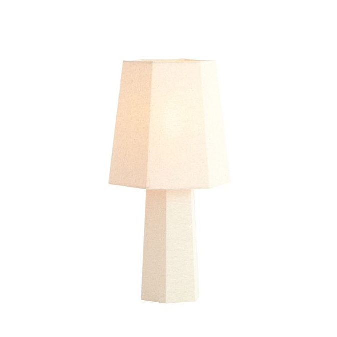 image cut out on white background of cream lamp with geometric shade and bulb inside emitting warm glow