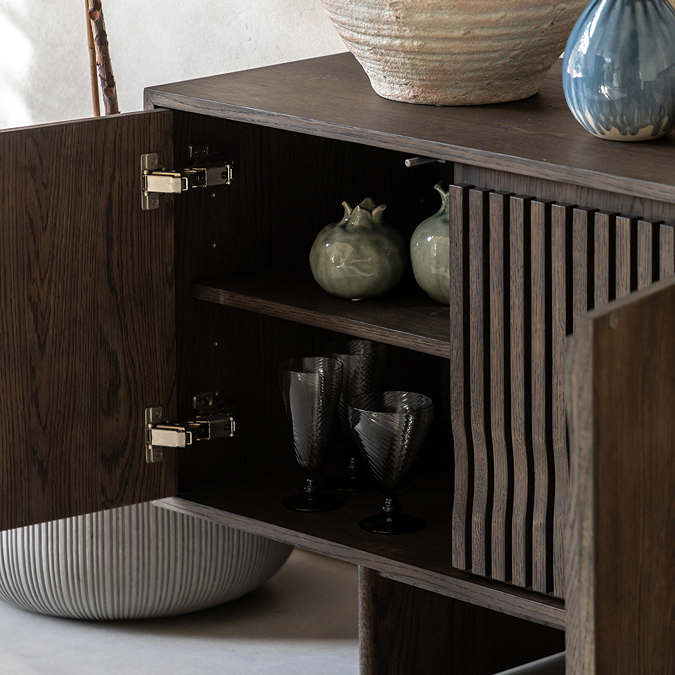 close up image of sideboard door open to reveal shelf space with crockery stored on it