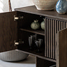 close up image of sideboard door open to reveal shelf space with crockery stored on it