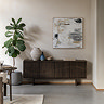 image of walnut 4 door sideboard with wave panel pattern, against a cream wall with neutral abstract art hanging above it