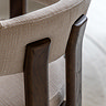 close up on back of natural upholstered dining chair in cream fabric, with ash wood legs stretching up the back