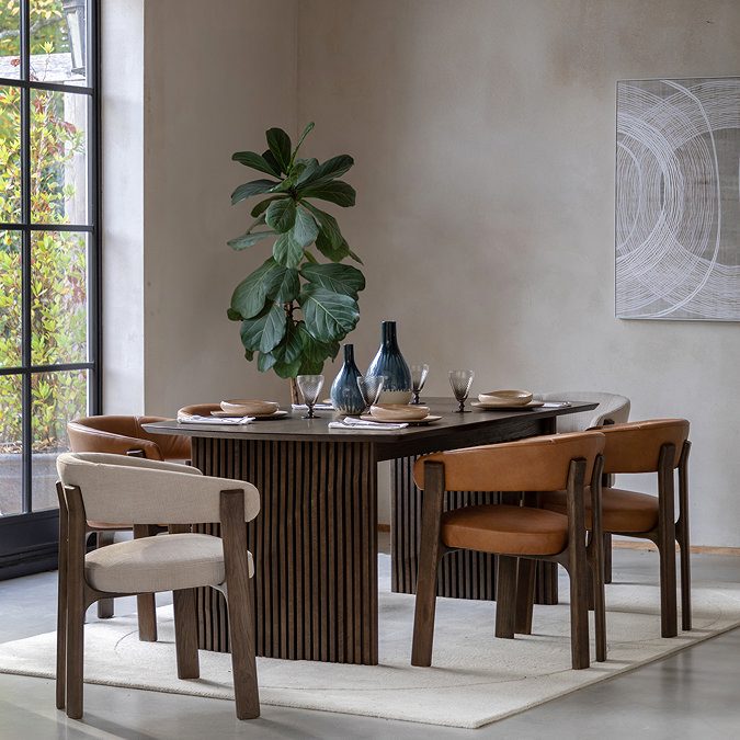 wide image of brown leather dining chair with matching natural version, tucked under walnut brown dining table
