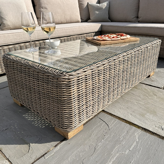 close up image of rattan glass-topped table as part of outdoor corner set
