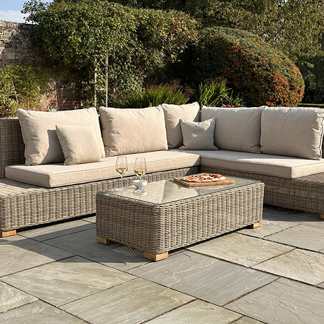 image of rattan five seat corner sofa set with matching rectangular table on flagstones of patio