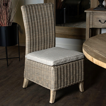 image cut out on white background of rattan dining chair with beige seat pad