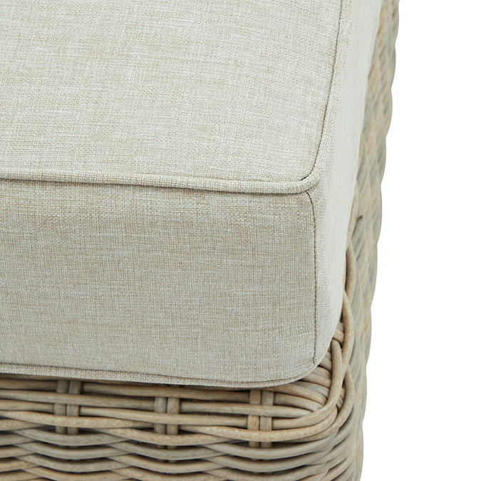 close up image of plush beige cushion of rattan garden footstool