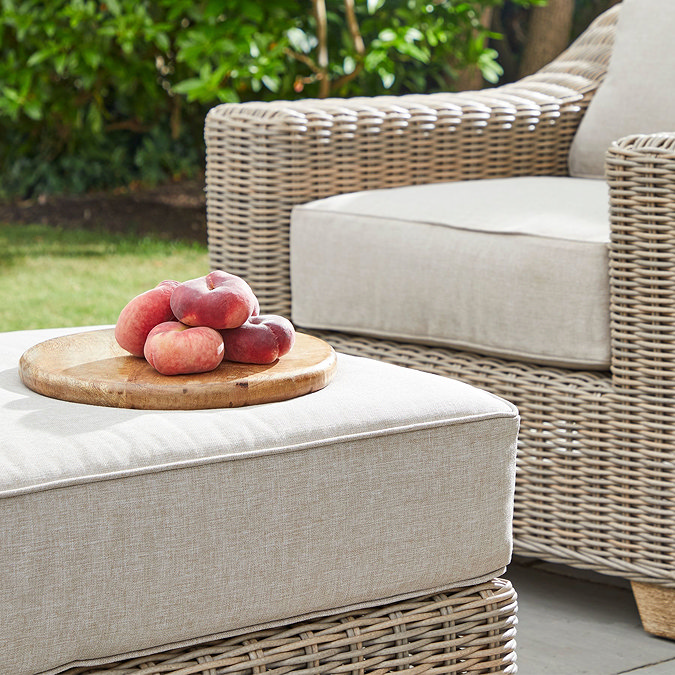 close up image of outdoor rattan footstool with plate of fruit on it
