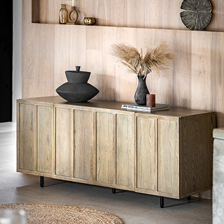 image of smoked oak panelled sideboard with 7 vertical panels, topped with a black vase and a faux plant