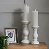 image of two column-inspired candle holders on a side table, holding battery operated candles