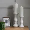 image of two column-inspired candle holders on a side table, holding battery operated candles