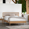 image of bed with rectangular horizontal fabric headboard and smooth oak frame, decorated with crisp white duvet and light brown throws