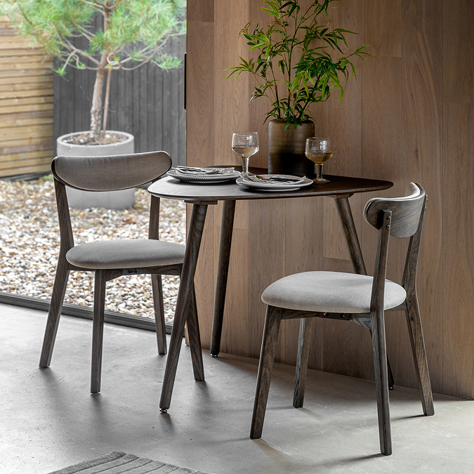 image of smoked oak triangular dining table against a wooden wall, with matching dining chairs