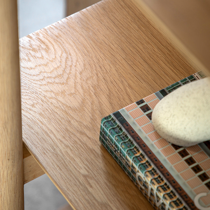 close up on smooth oak grain on surface of shelving unit, with book slightly in shot