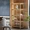 image of light oak tall shelving unit with five shelves populated with home accessories such as vases, books, and glasses