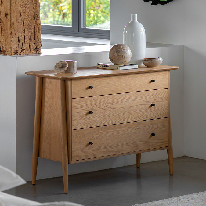 image of minimalist light oak 3 drawer chest with angled legs and small round handles, topped with small vase and books