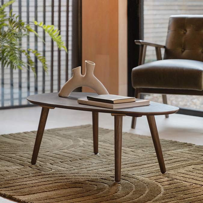 image of oval smoked oak coffee table on dark geometric rug in living room