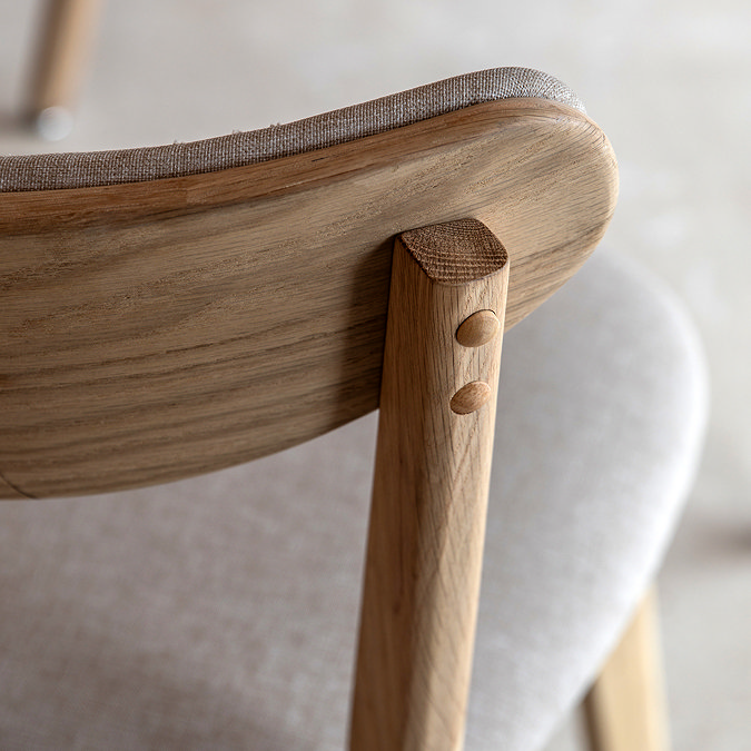 close up image of curved back of dining chair with light oak frame