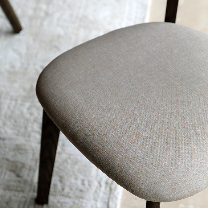 close up image on fabric padded seating of dark wood dining chair