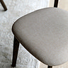 close up image on fabric padded seating of dark wood dining chair