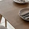 close up image on smooth oak surface of dining table, neutral coloured plates partially in shot