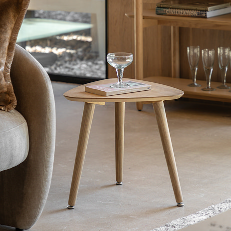 triangular side table in wooden oak next to a grey armchair