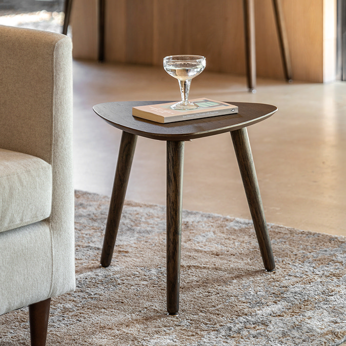 image of triangular smoked oak side table next to a cream sofa on a brown rug