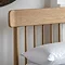 close up on spindled headboard of light oak bed with slightly curved edge
