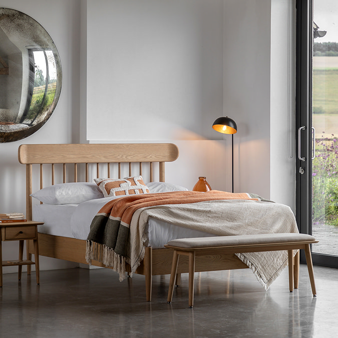 light oak bed with spindled headboard and decorated in warm duvet and throws