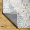 close up image of blue and white distressed vintage rug with corner folded over to show material underneath