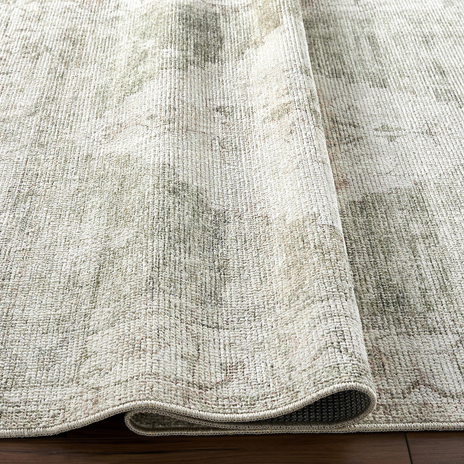 close up image of olive green and ivory vintage rug, ruched up to show its thinness