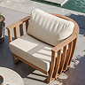 close up image of outdoor sofa with teak arms and plush cushion