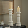 image of two ribbed ceramic pillar candles standing on a sideboard, containing battery-operated candles