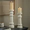 image of two ribbed ceramic pillar candles standing on a sideboard, containing battery-operated candles